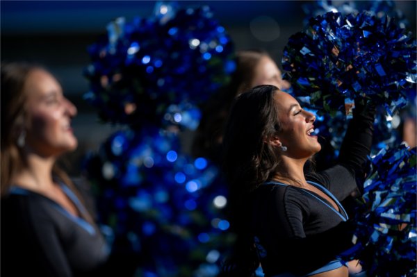 Members of the Laker Dance Team smile while waving shiny blue pompoms.