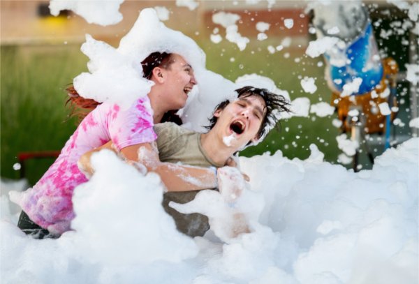 Two Grand Valley students laugh while covered in foam in a foam pit at Laker Kickoff.