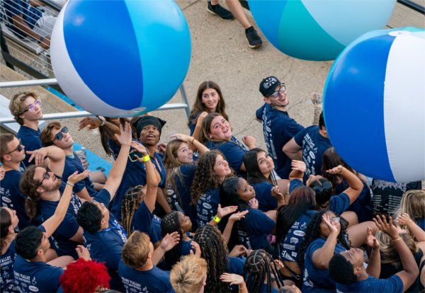Grand Valley students pass large white, blue and aqua beach balls among themselves.