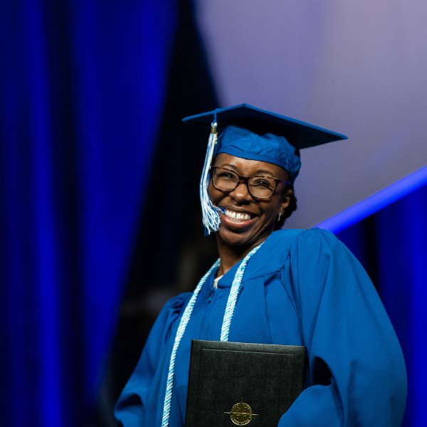 A graduating student smiles after accepting her degree at commencement on December 10.