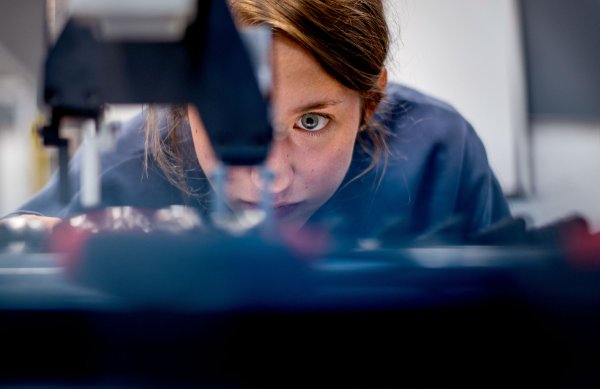 A engineering student's eye looks intently at a piece of equipment.