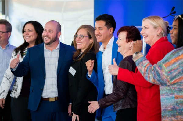 group of people standing in row after cutting a ribbon, lots of smiles