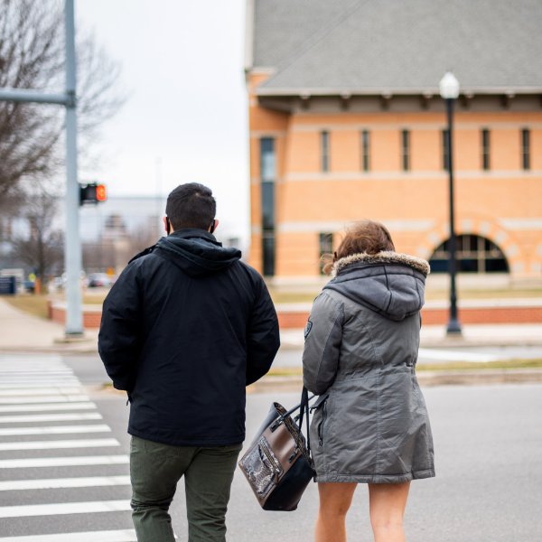 Two students cross the street in front of Secchia Hall on the Pew Grand Rapids Campus.
