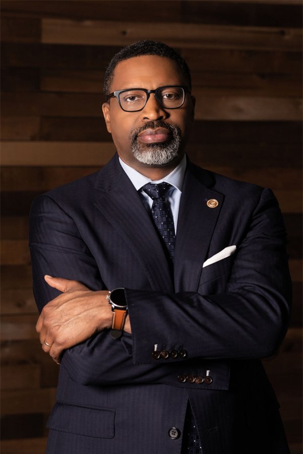 Derrick Johnson in dark suit, arms crossed