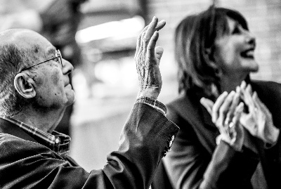 Bob Thompson waves to a student as President Philomena Mantella applauds during an event.