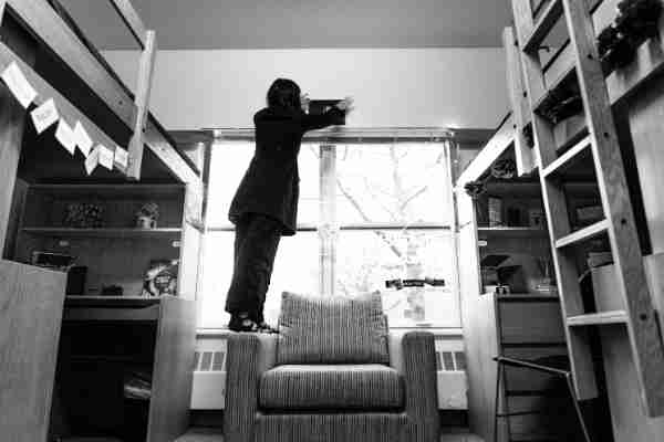 A black and white photo of a GVSU employee decorating an empty room for "Room Splash"