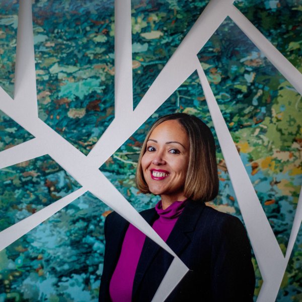 A portrait of Alisha Davis. She is standing in front of a piece of artwork, with it broken apart to look like a mosaic.