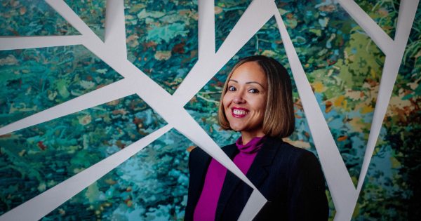 Alisha Davis poses in front of a piece of artwork that has been digitally altered to look like a mosaic. 