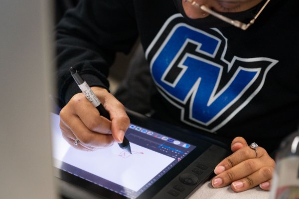 A student wearing a GV sweatshirt uses a writing instrument to draw on a screen.