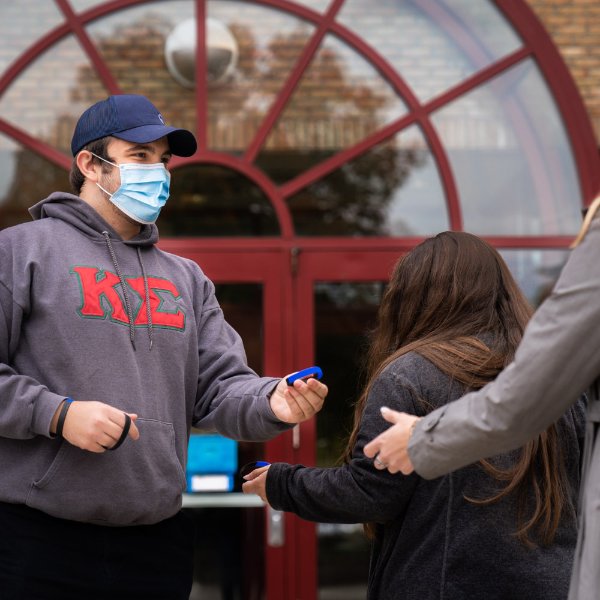 Vito Cannizzaro, a Grand Valley student, hands out wristbands to students who are using COVID-safe behavior.