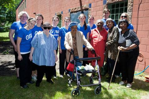 Nursing students and members of the United Methodist Community House stand by a garden that the students planted at the center.
