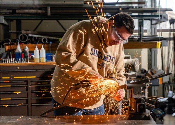 Sparks fly as mechanical engineering major Scott Strayer grinds a sword for a video crew at the Kennedy Hall of Engineering 