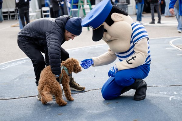Louie the Laker pets a small dog during the Homecoming tailgate.