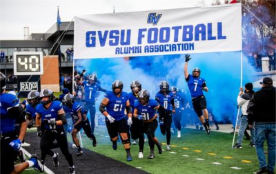 Football players enter the field for the Homecoming game. 