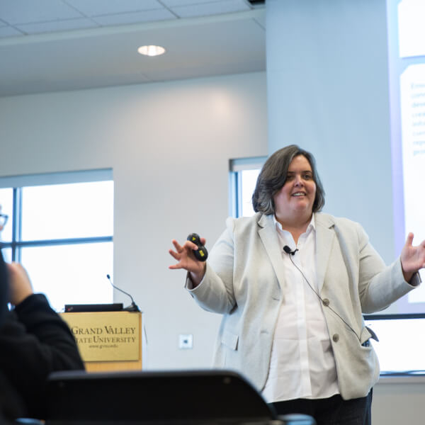 Woman stands with arms apart in front of podium.