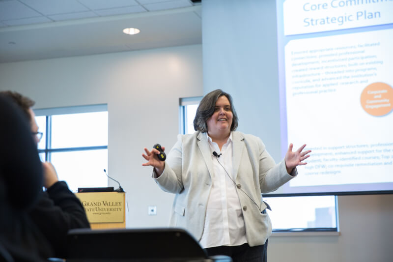 Woman stands with arms apart in front of podium.