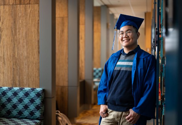 Long Ho poses in academic regalia in the Mary Idema Pew Library
