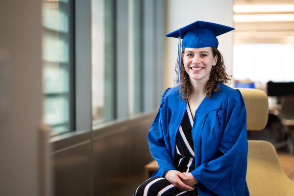 Grace Pallissard poses in academic regalia in the Mary Idema Pew Library 