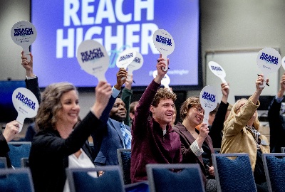 Attendees at the GVSU Board of Trustees meeting raise paddles in support of the Reach Higher Together strategic plan.