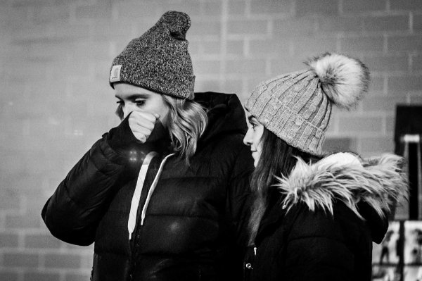 Black and white image of two people in coats and hats.