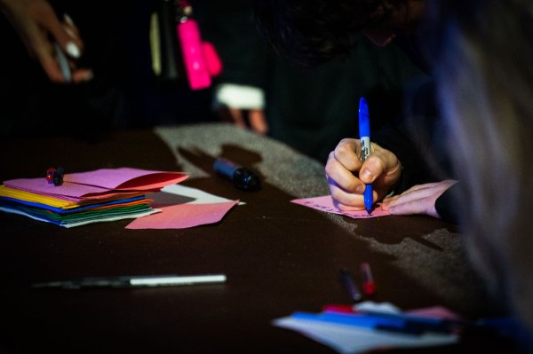 image of a hand holding a sharpie writing on a notecard.