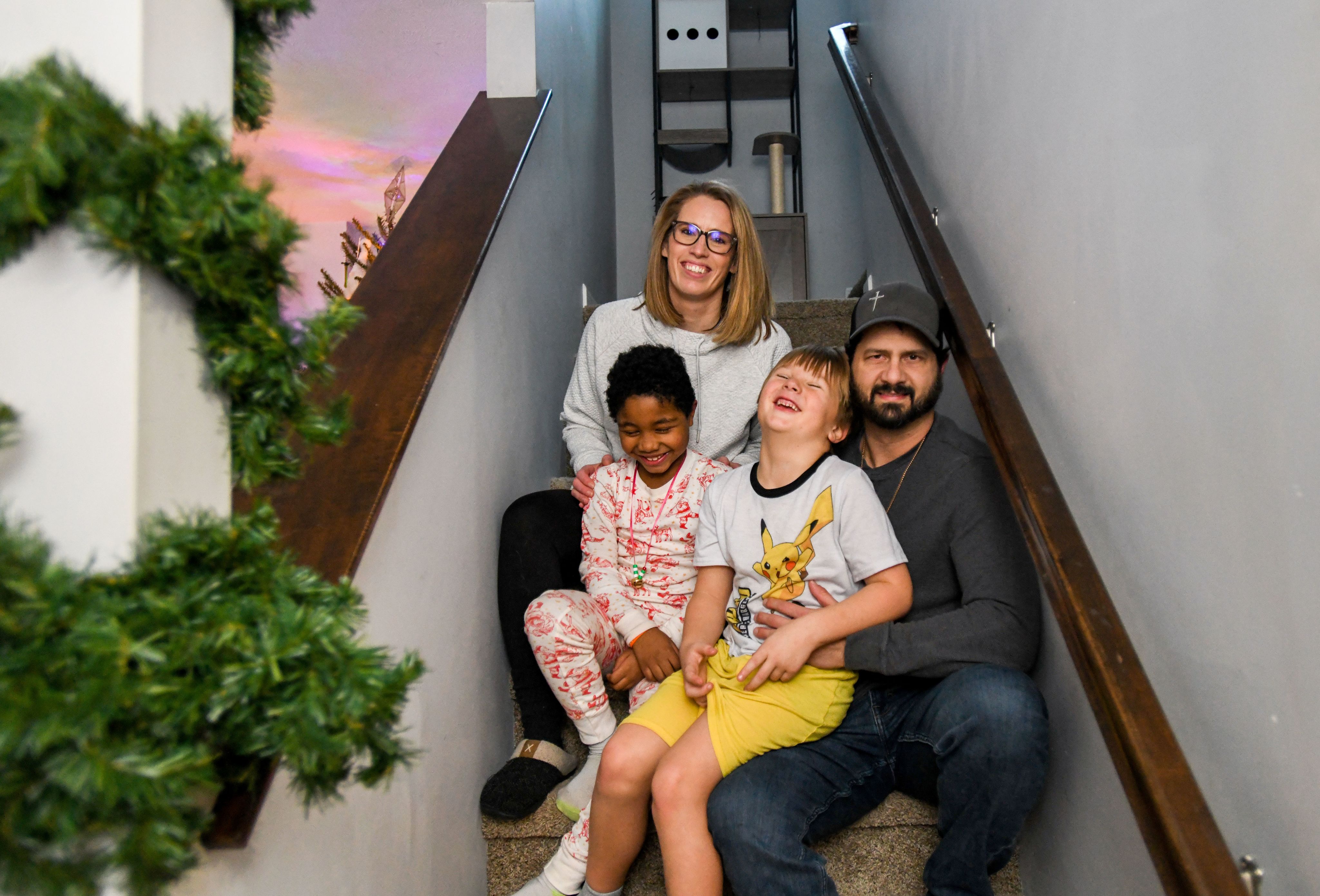 A family smiles while sitting on the steps of a stairwell.