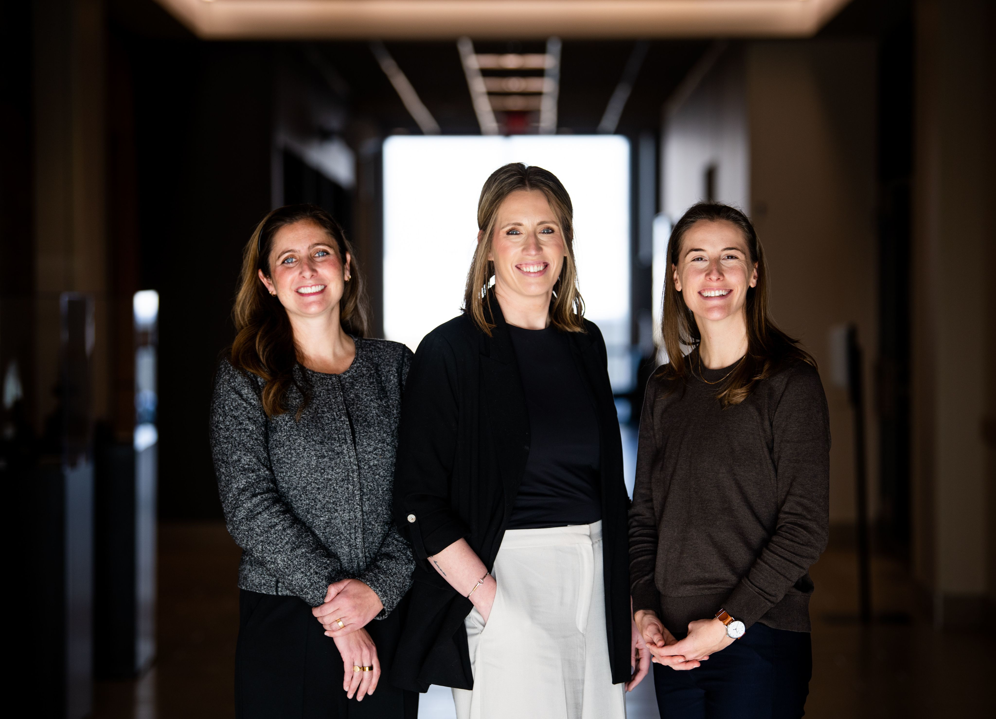 Three individuals stand in a hallway.