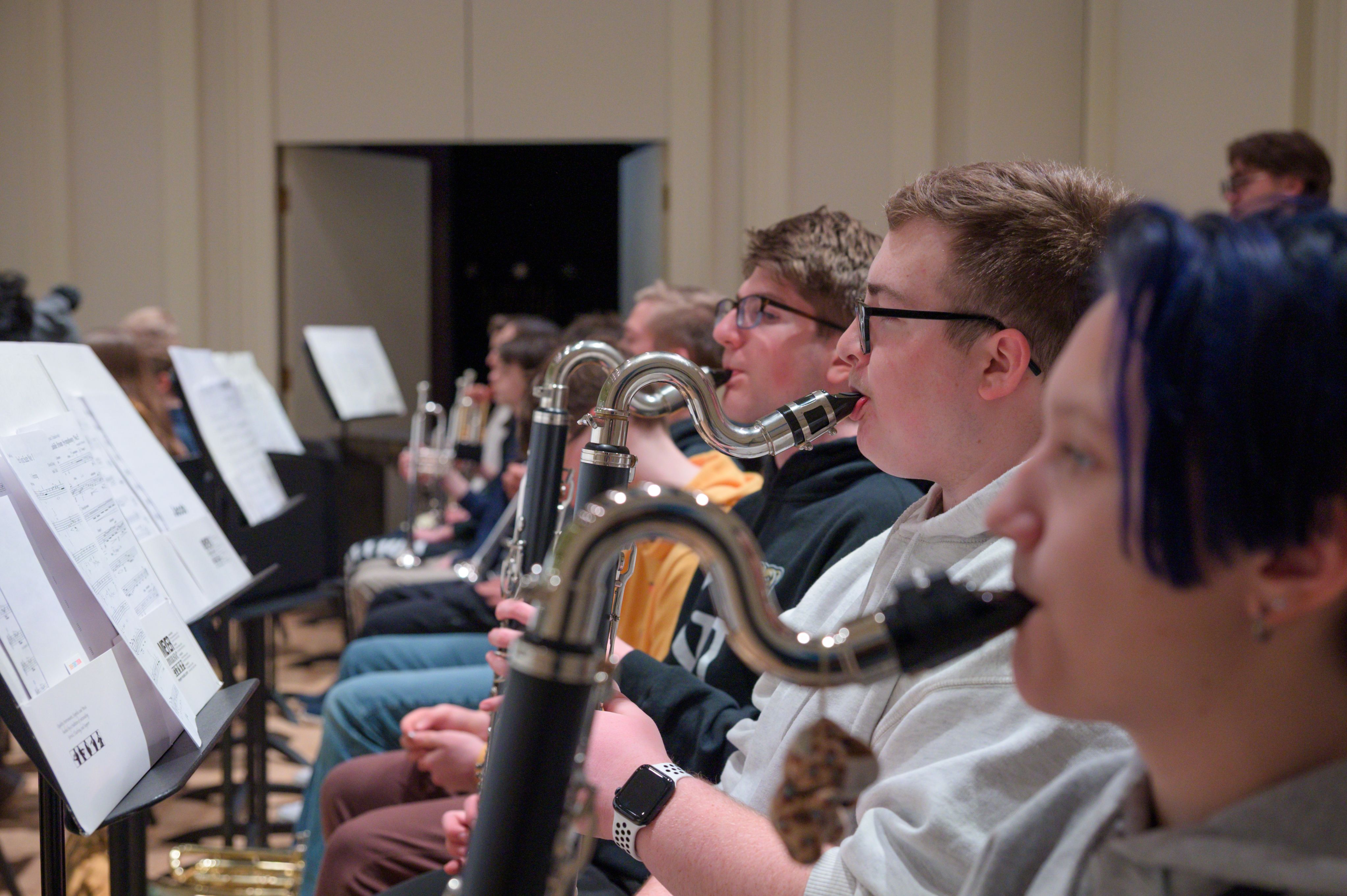 students playing bass clarinets with music stands in front of them