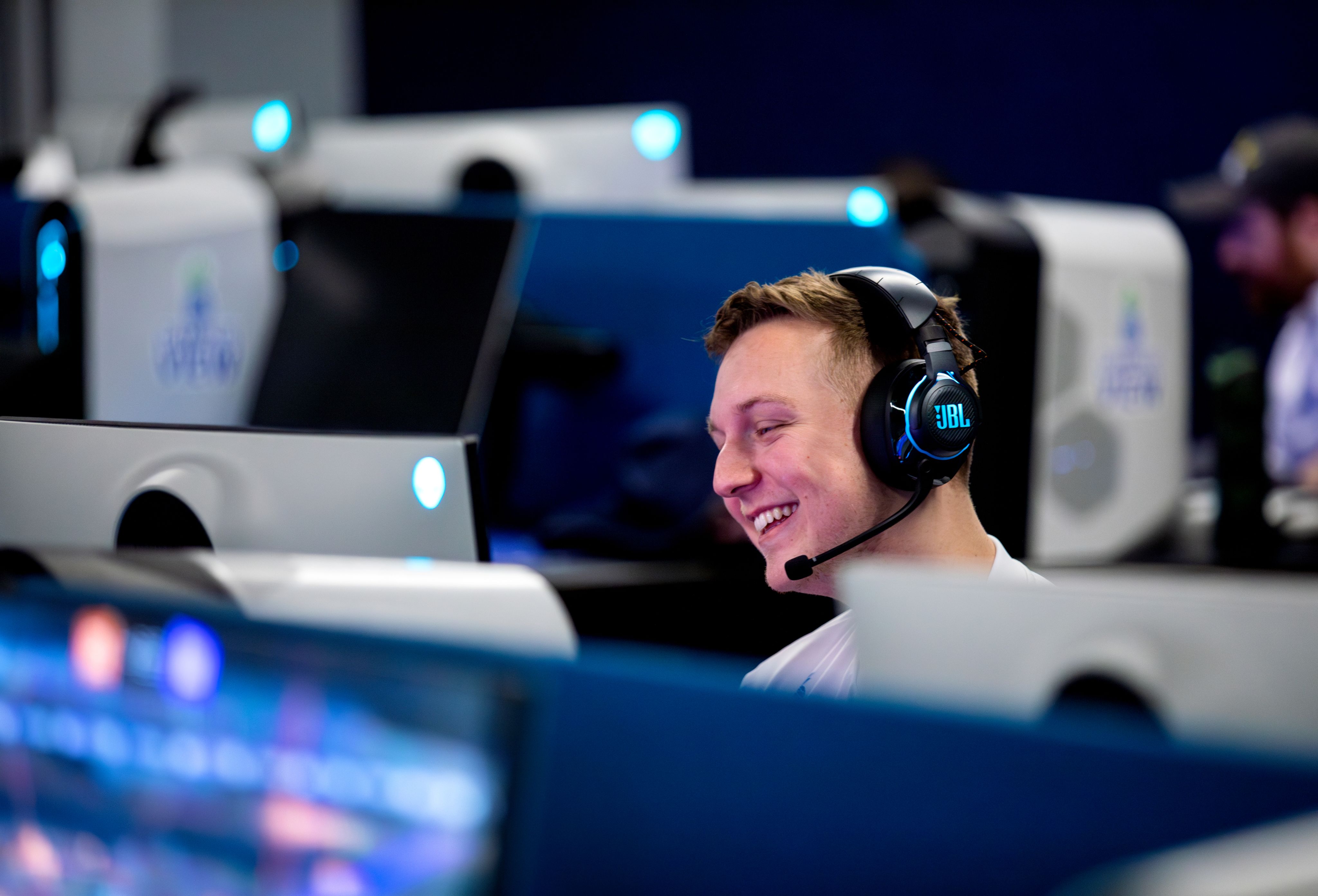 student smiling behind gaming computer, wearing headphones