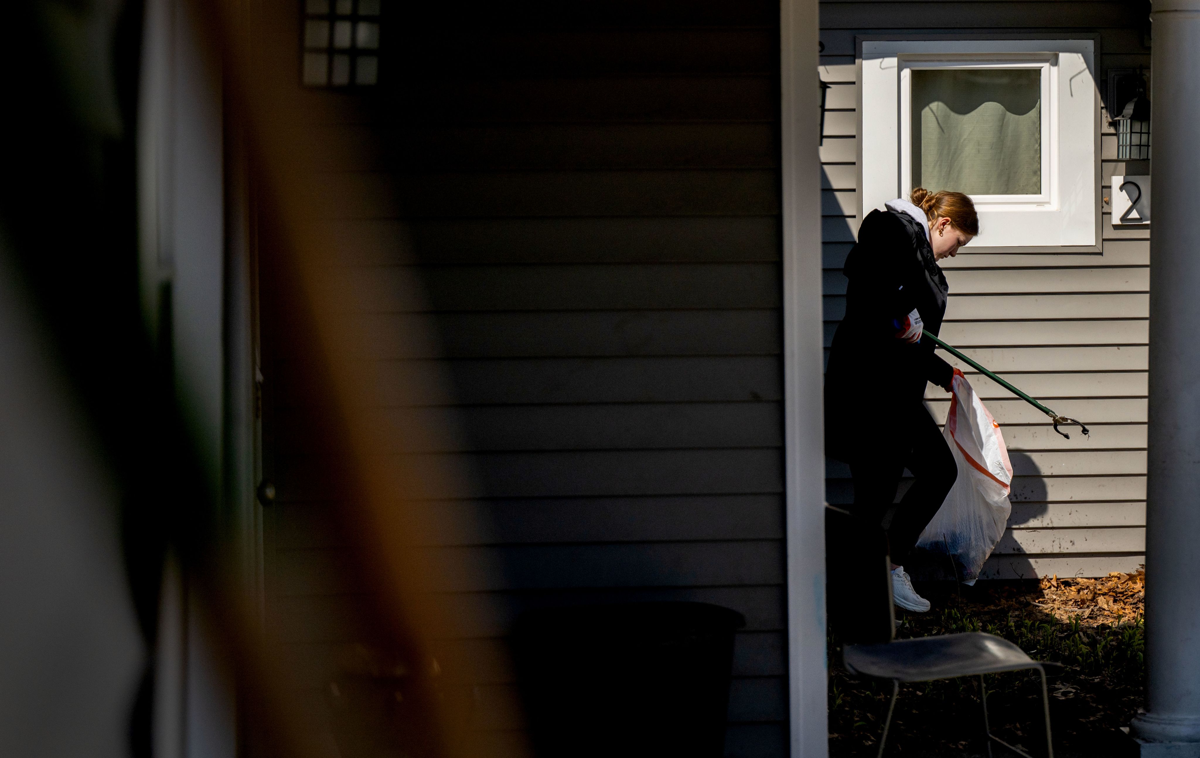 student outside with trash bag picking up garbage