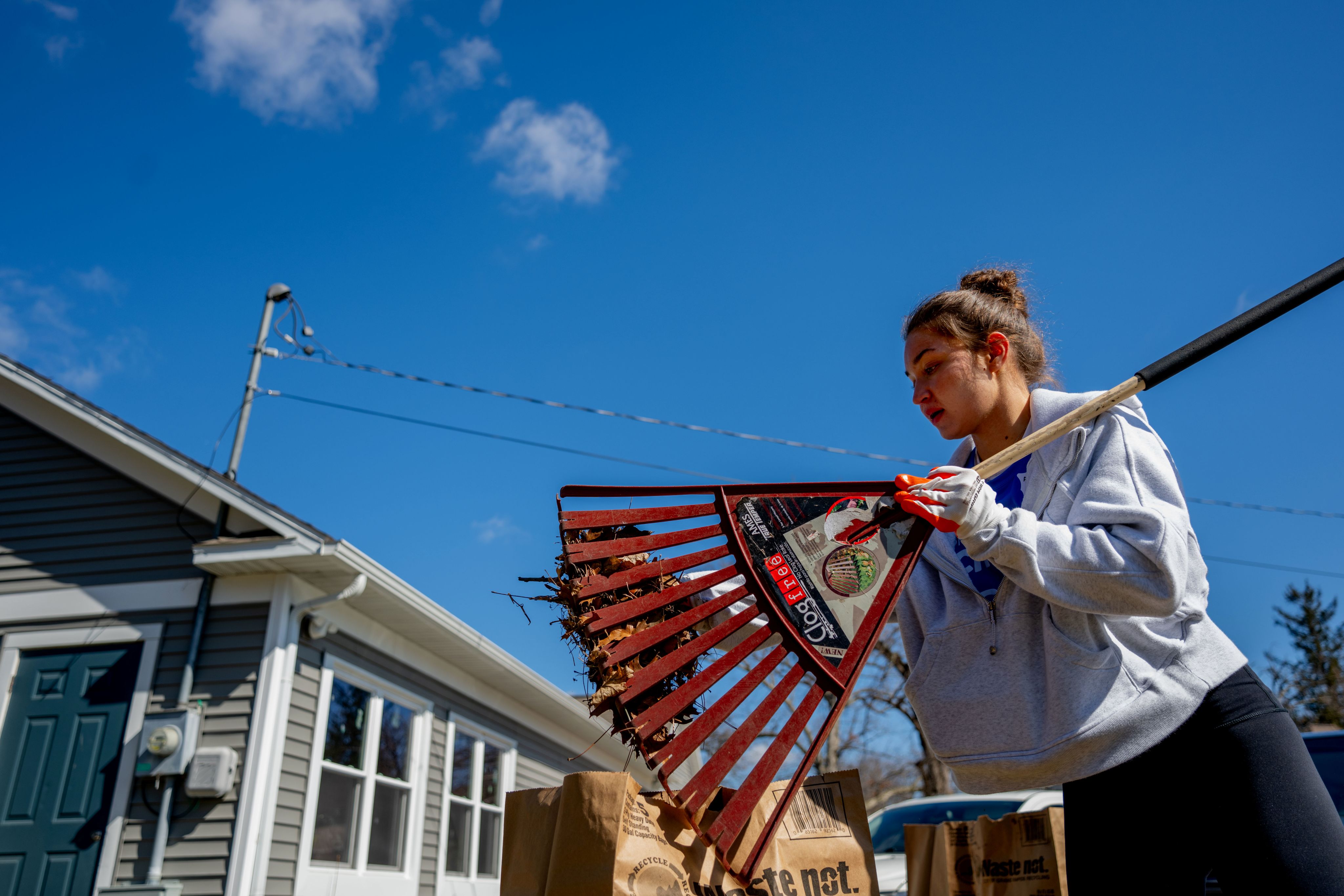 student raking leaves outside 