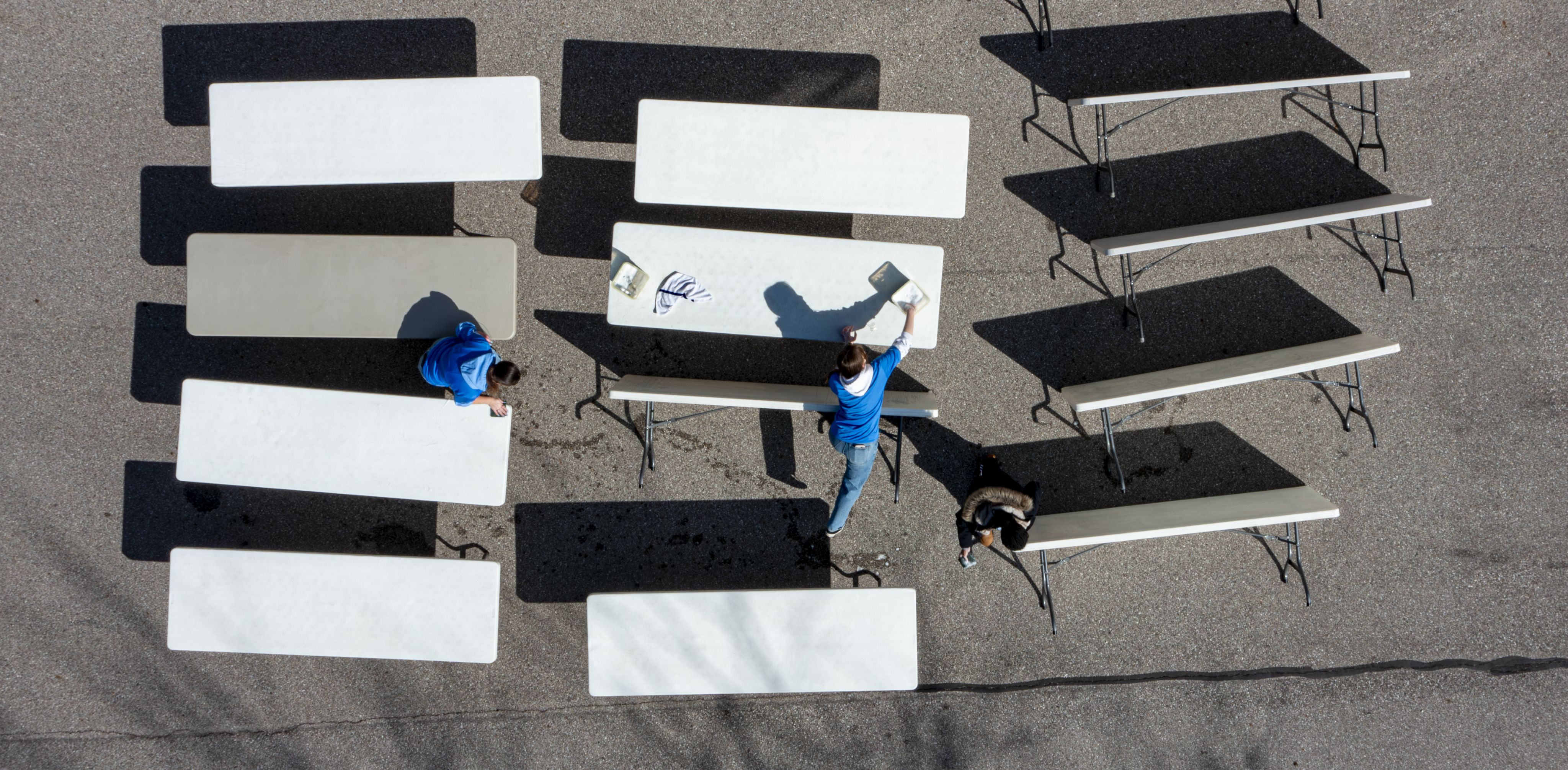 drone photo of students in blue tshirts cleaning white rectangular tables