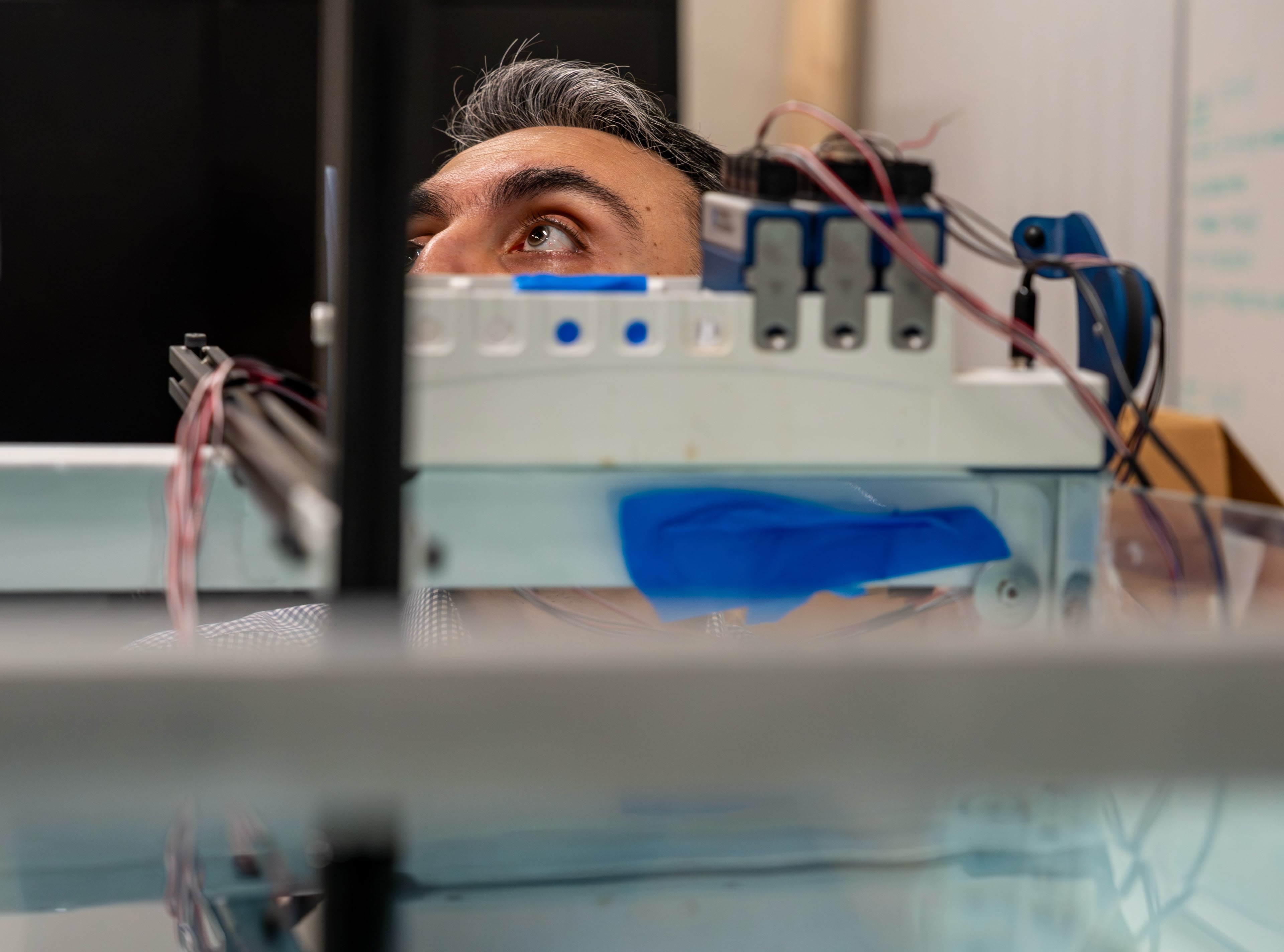 A person's eye is seen behind the top of a water tank's equipment.