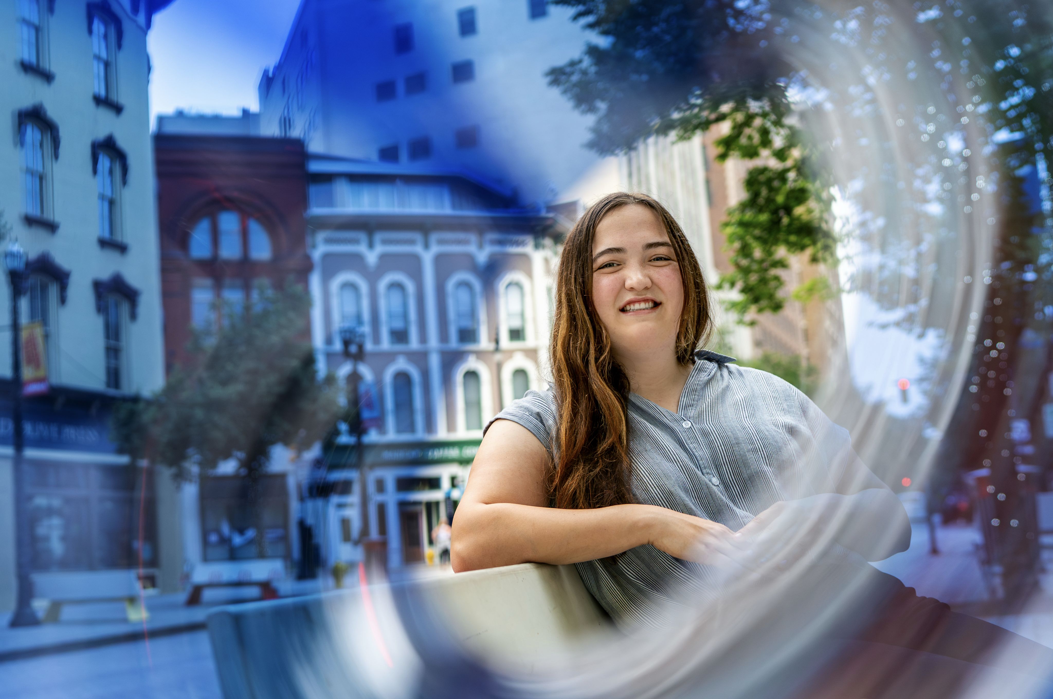 A person poses with buildings in the background. 