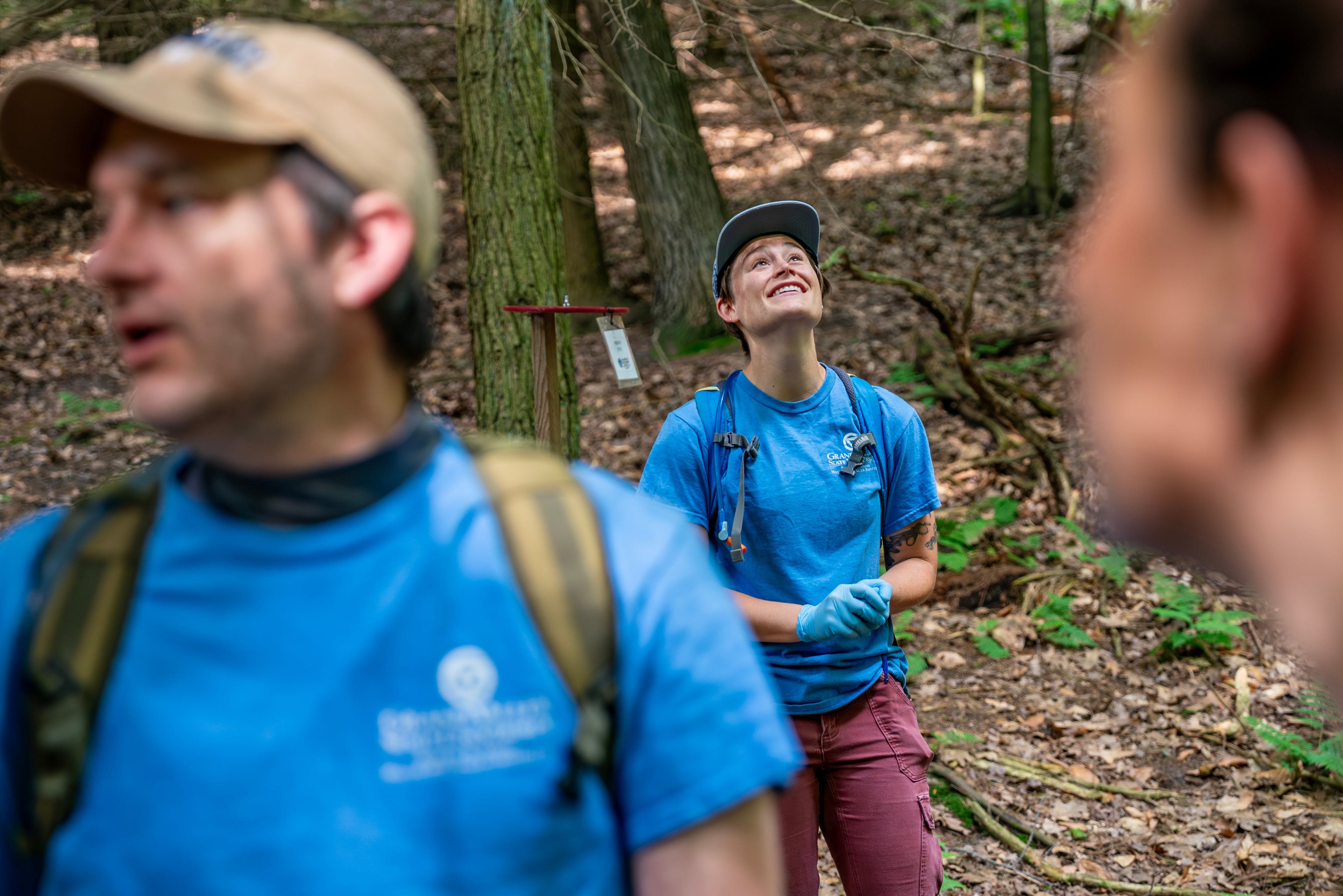 A person smiles as they look upwards while a person in the foreground talks. 