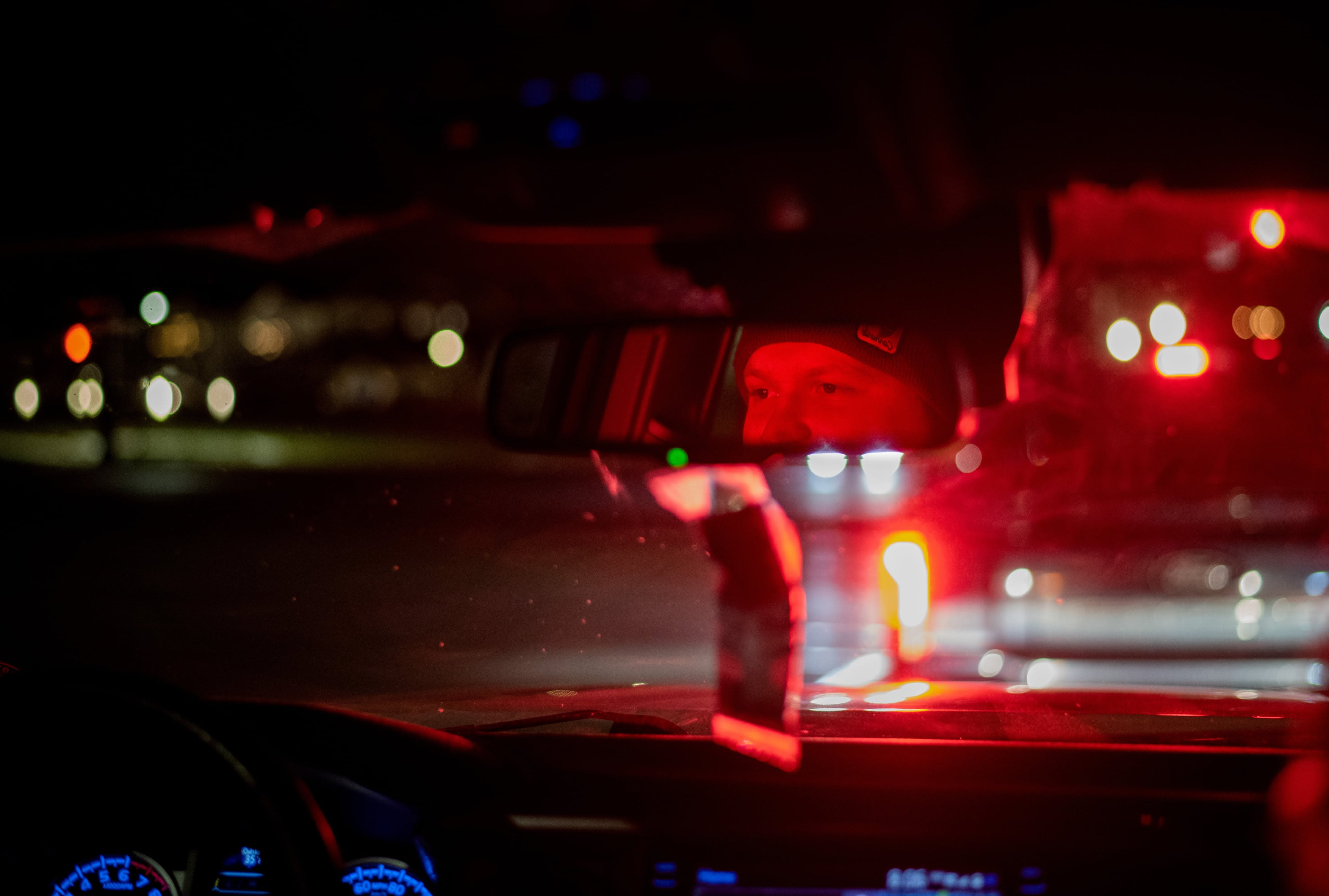 A person's eyes seen in the rearview mirror, illuminated by red light.