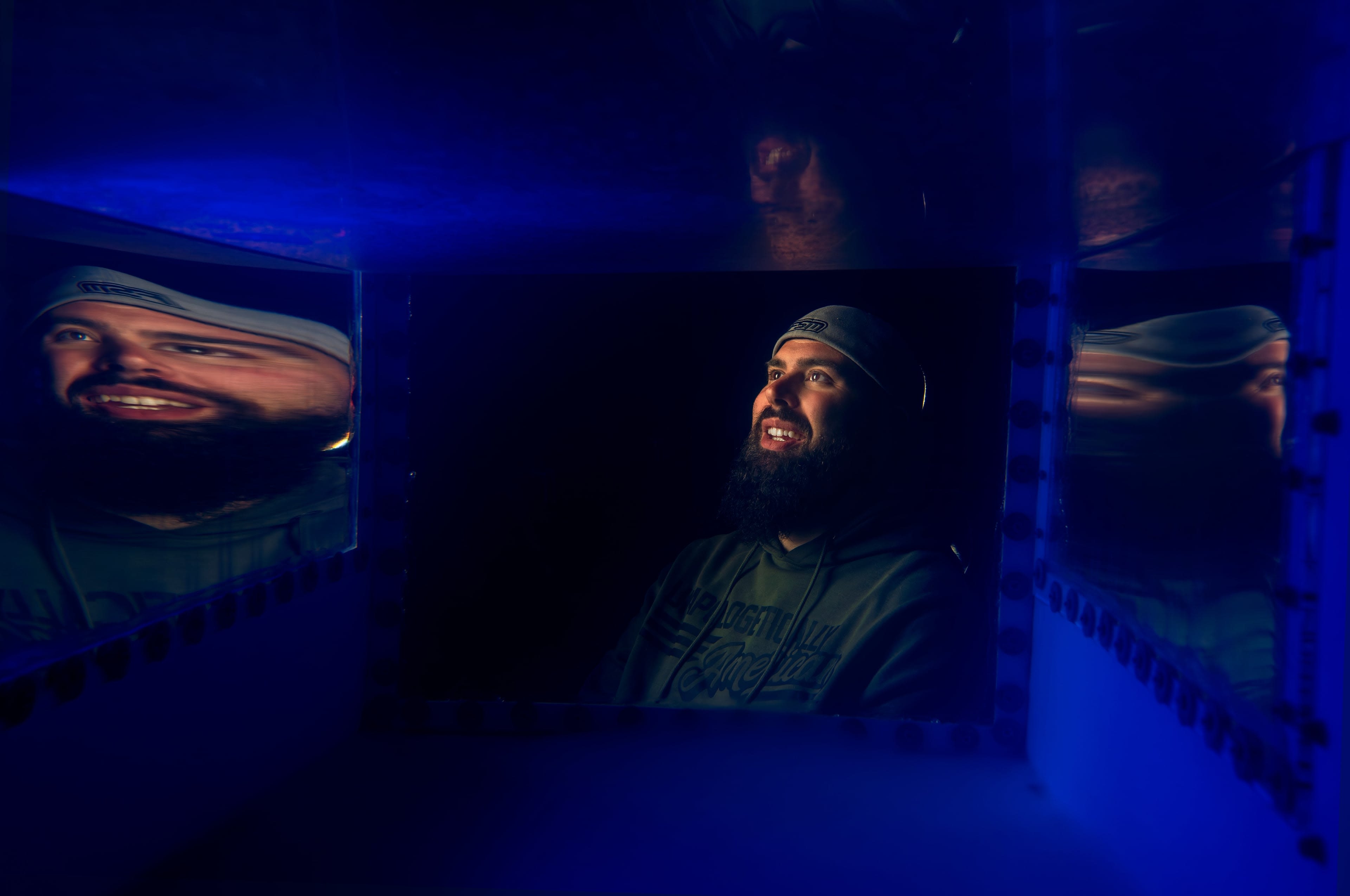 A person's face illuminated by light, gazes upwards. In the foreground, a box filled with blue light shows the person's reflection.