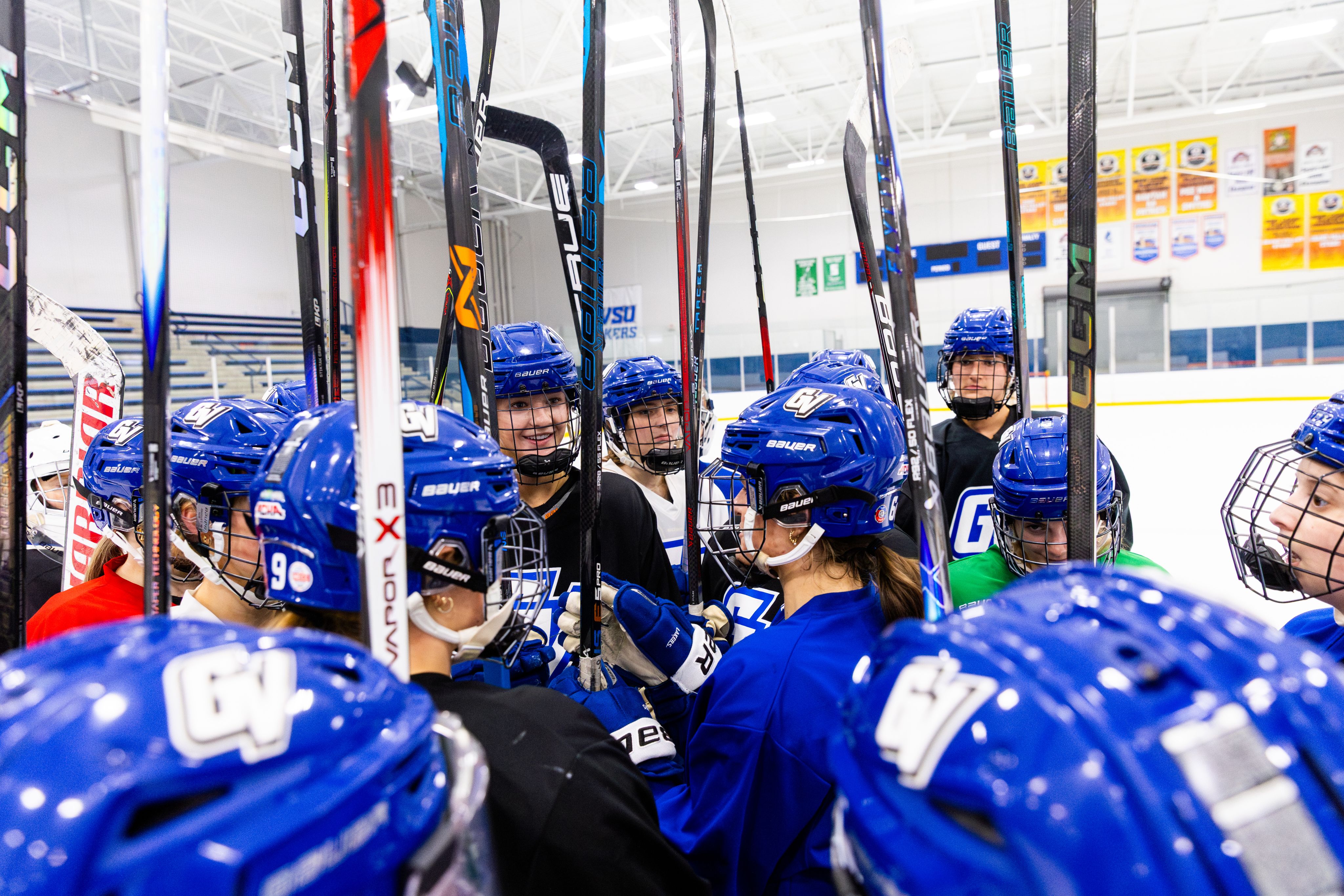 A hockey team gathers together, raising their sticks up in the air.