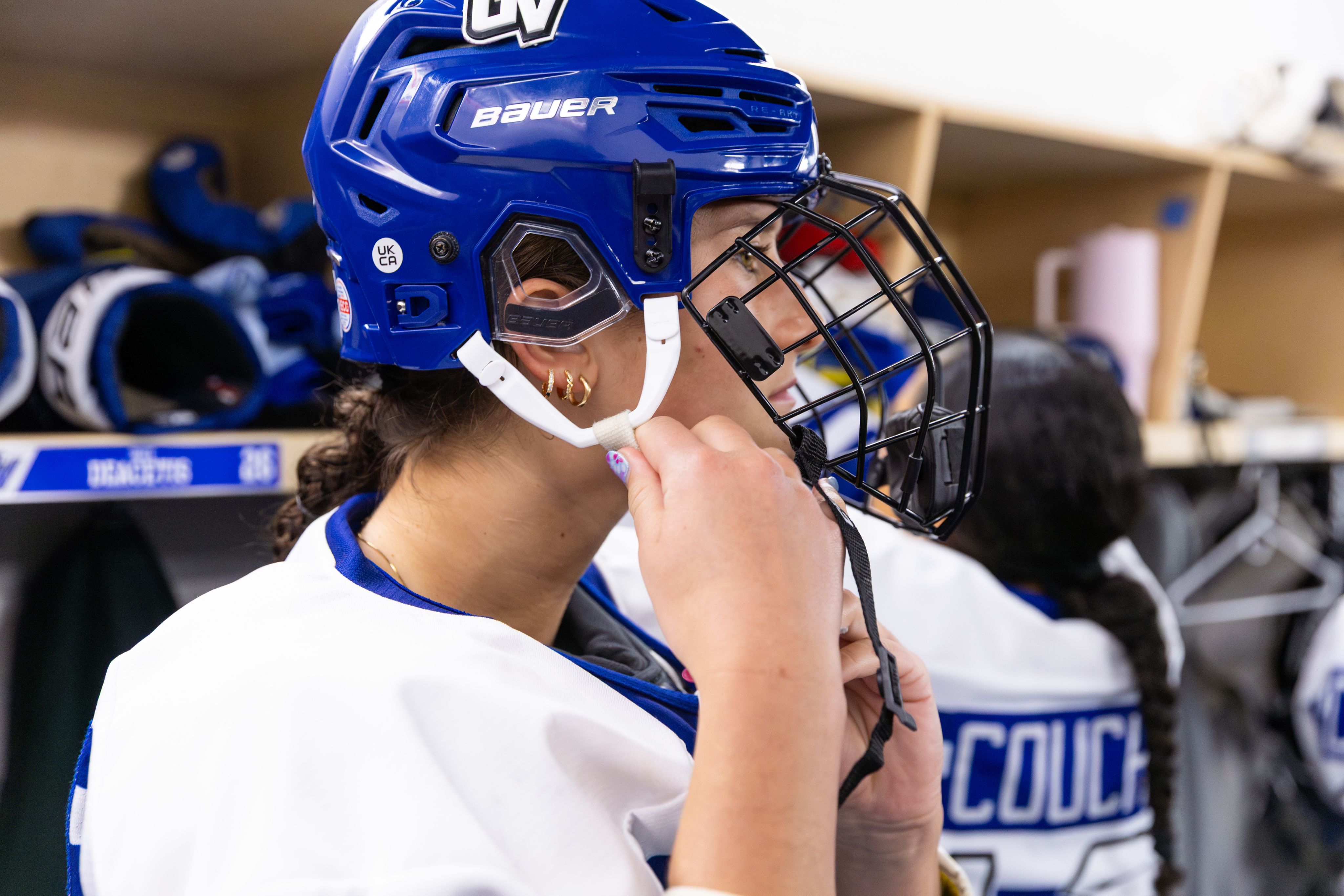 A hockey player fastens their helmet.