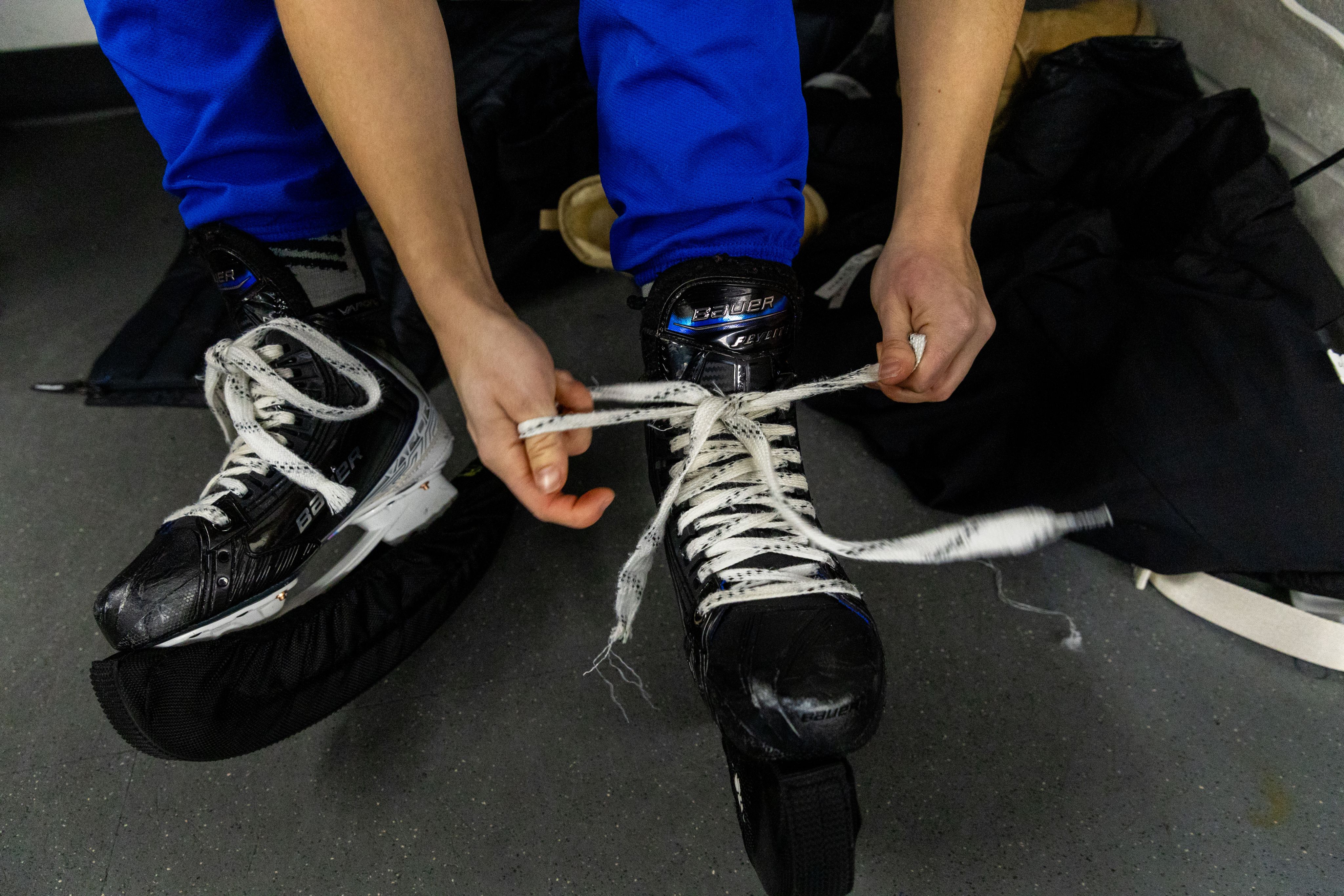 A close-up of a hockey player lacing up their skates.