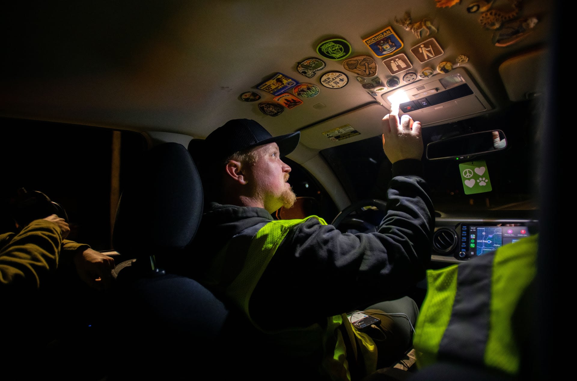 A person in a dark car activates a light while colorful patches decorate the ceiling.