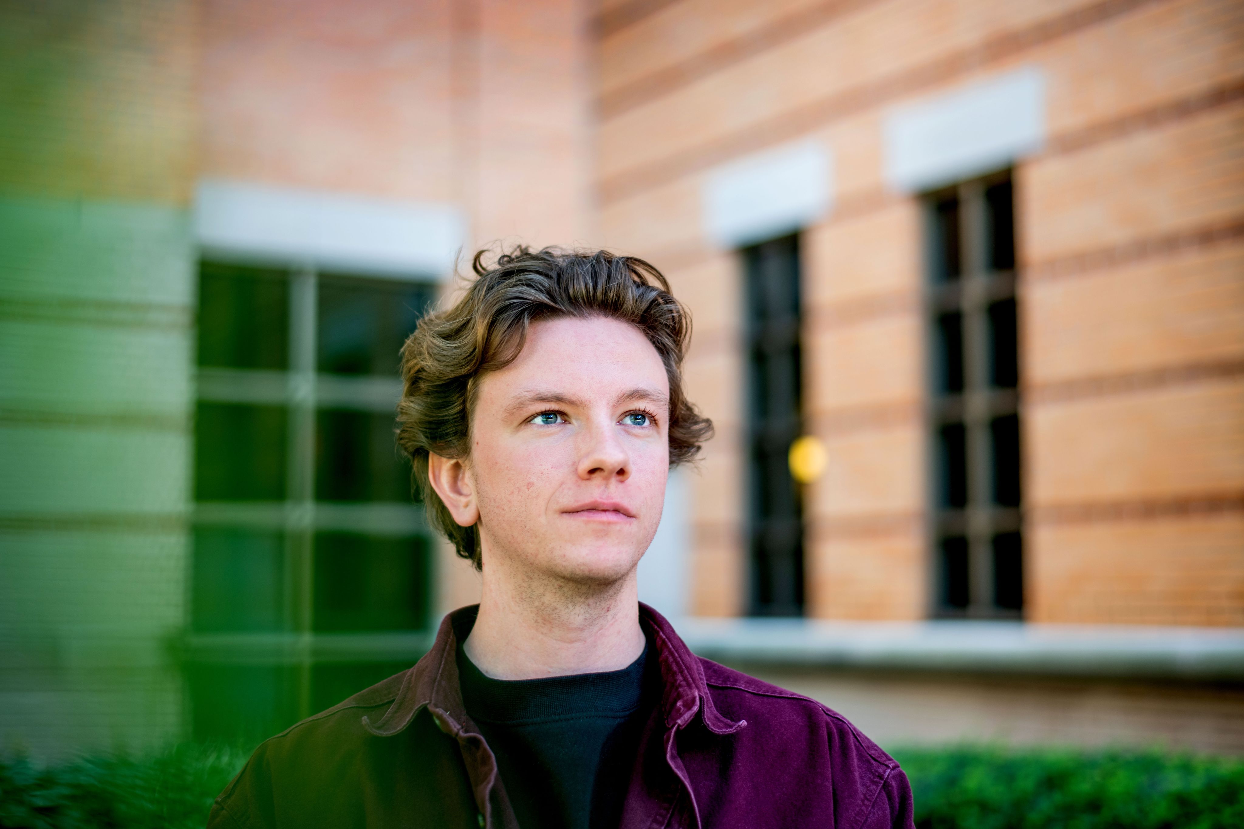 A person looking upwards with a blurred building in the background.