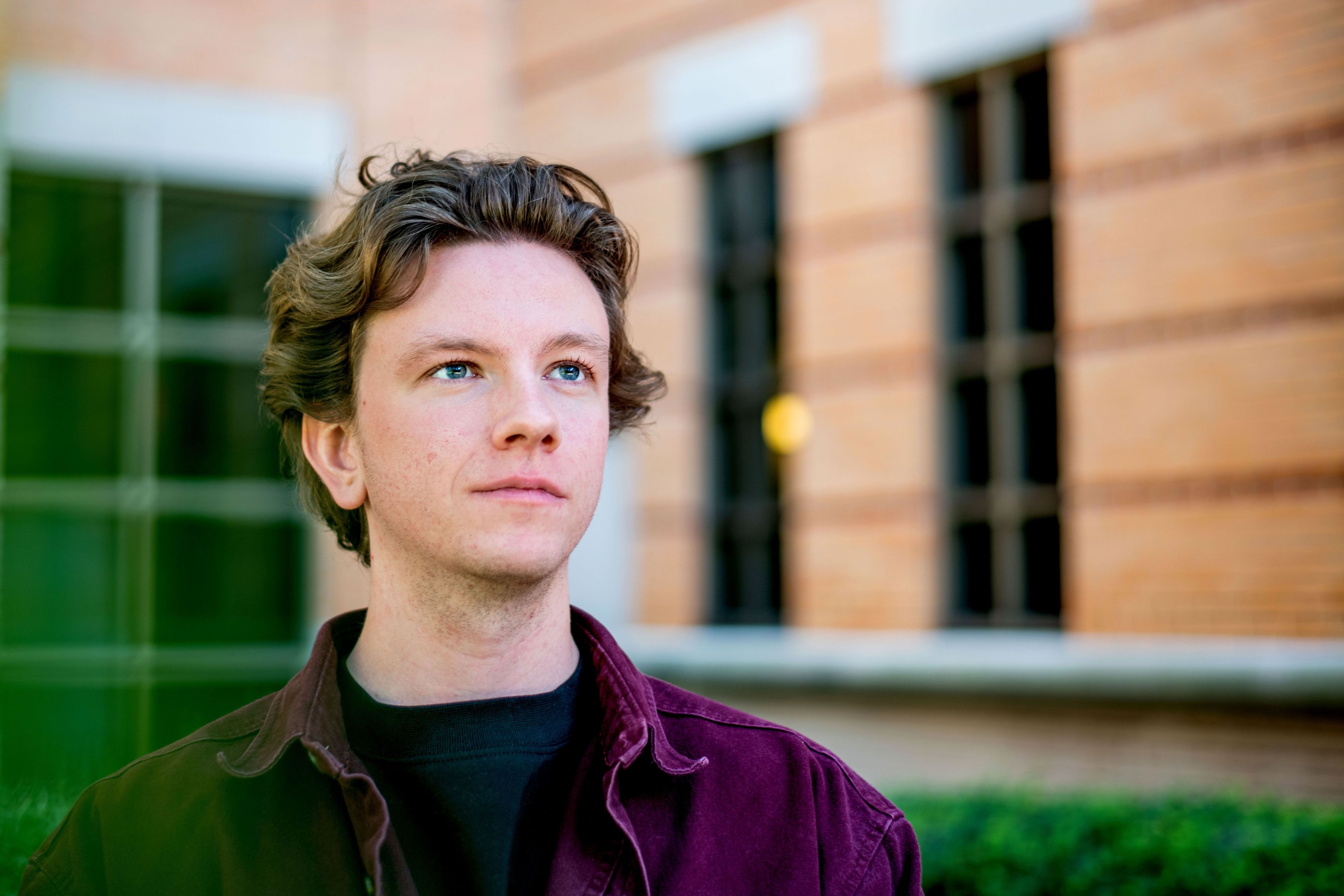 A person looks upwards with blurred buildings in the background.