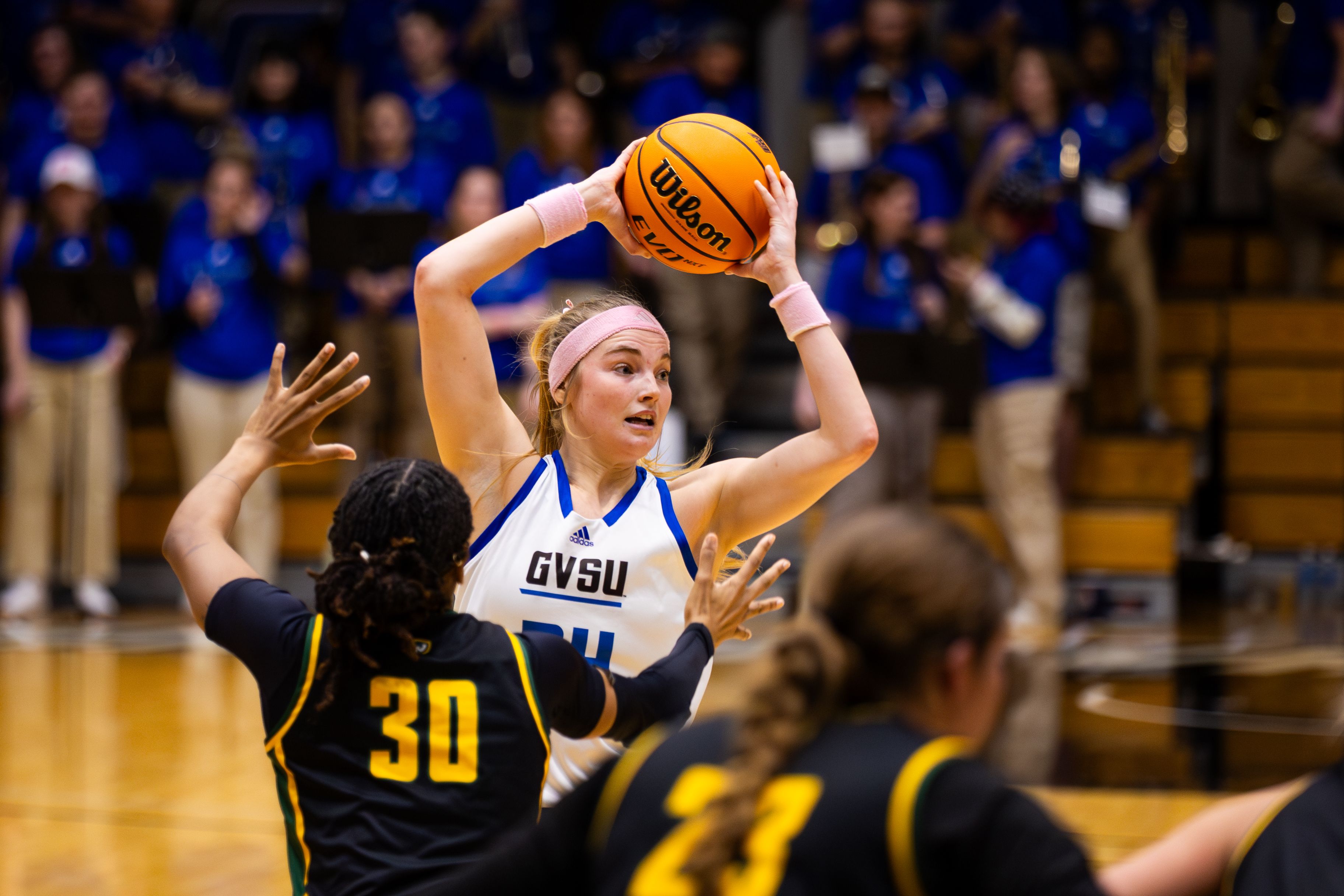 A Grand Valley basketball player, guarded by a Wayne State defender, prepares to pass the ball during a game.