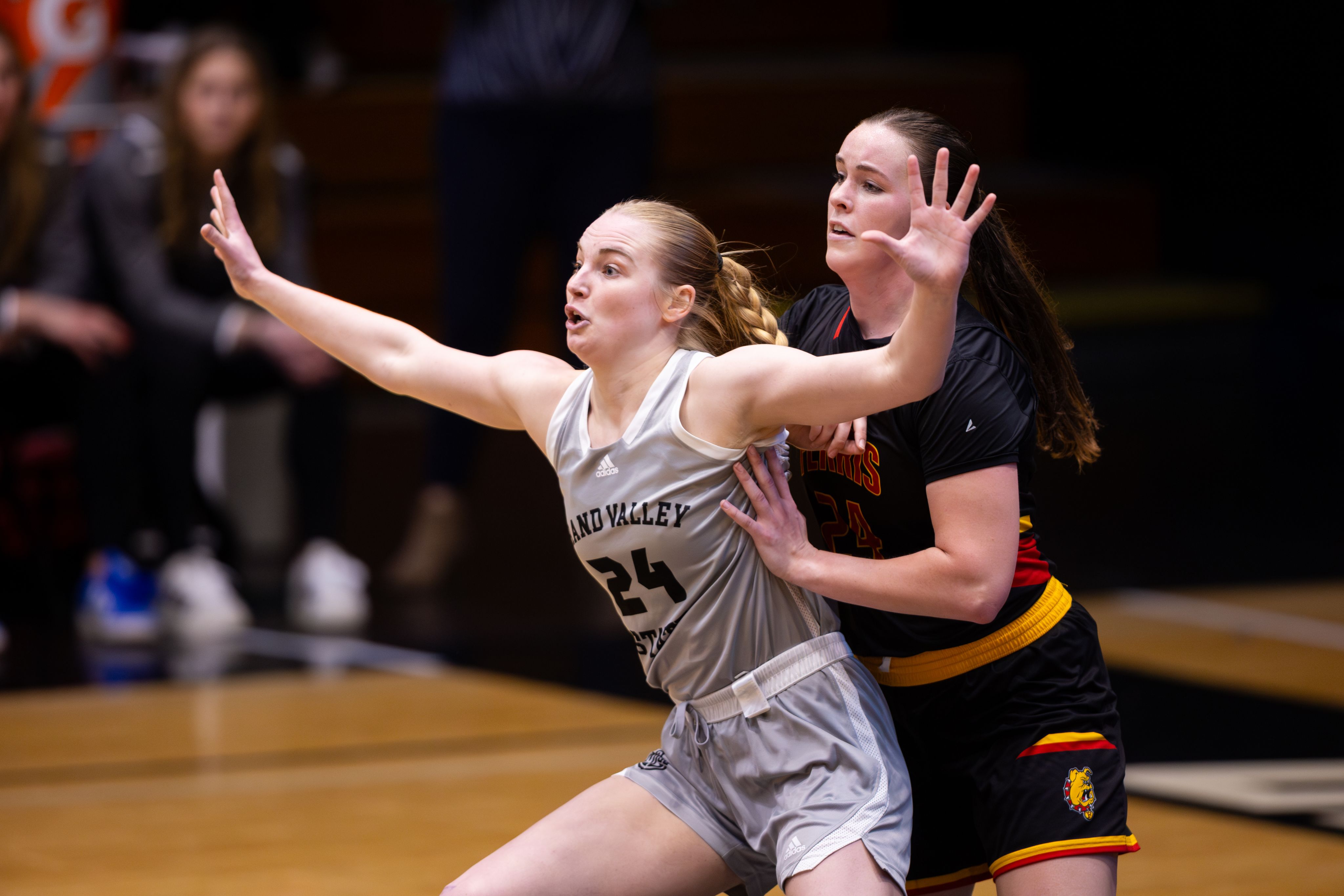 A Grand Valley basketball player in a defensive stance, arms extended wide, closely guarded by an opposing player from Ferris State during a game.