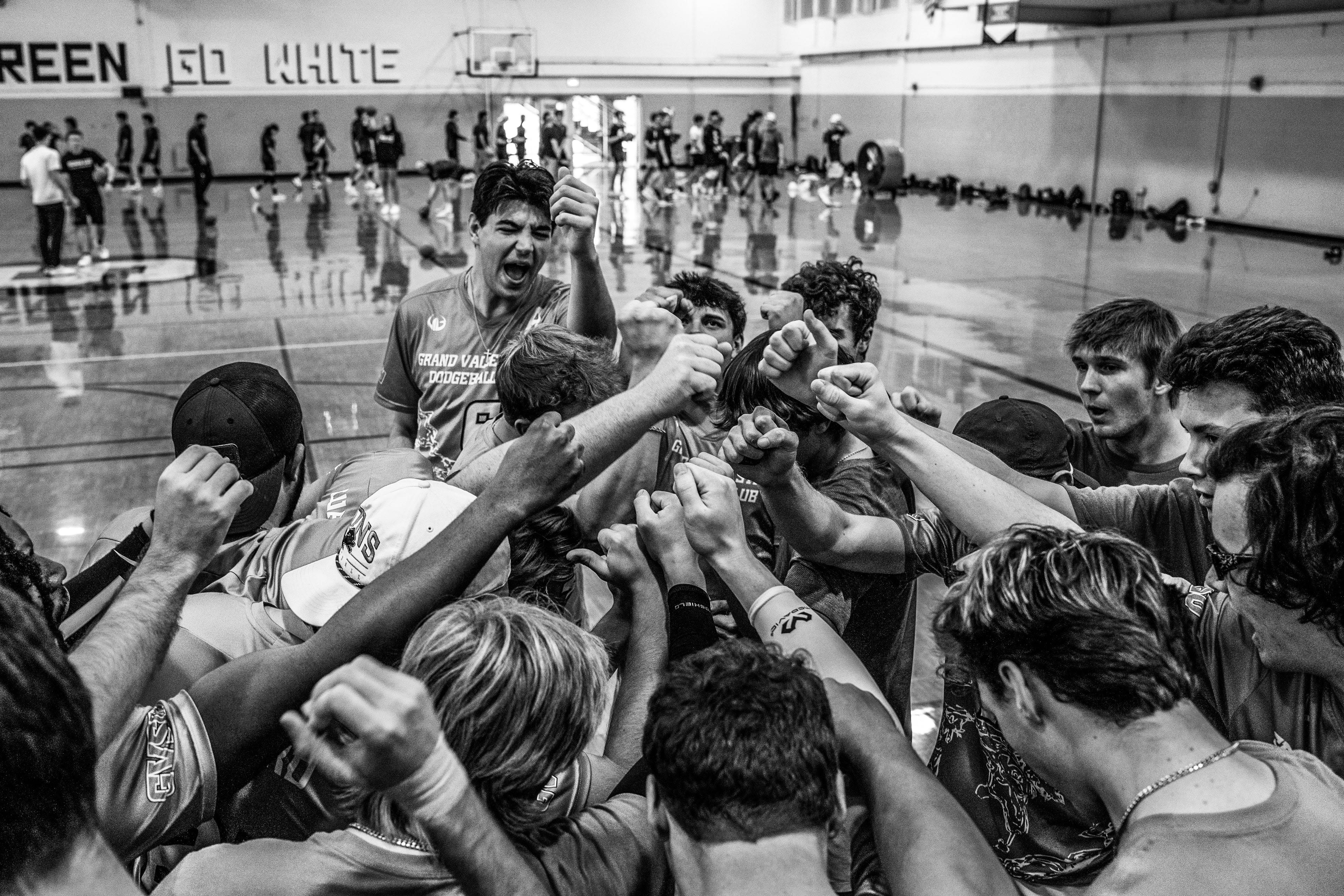 A black and white image of a group of people raising their fists as a team.