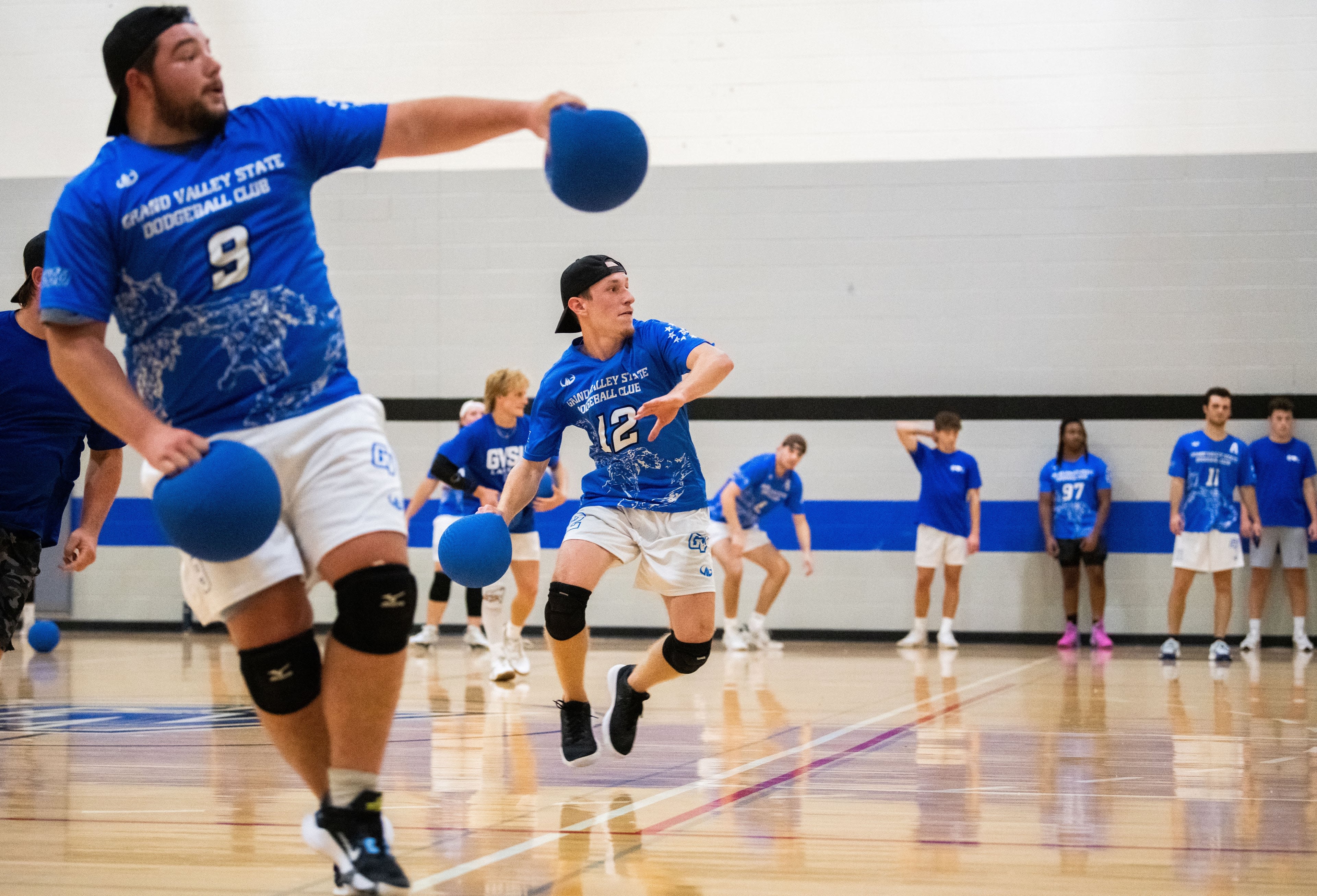 Two dodgeball players hold dodgeballs, one winding up to throw.