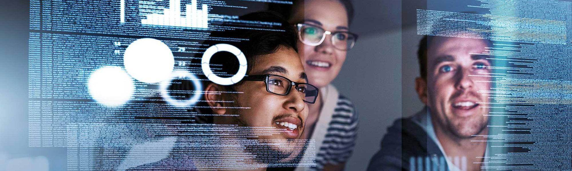 Photograph of the reflections of three students reviewing code on a computer monitor.