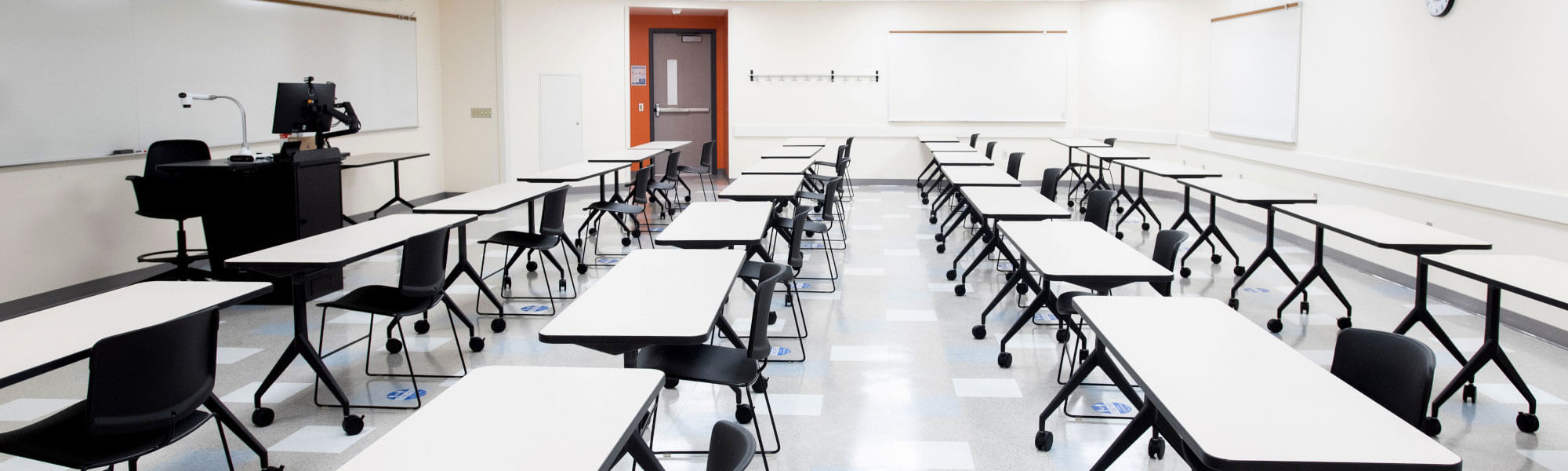 Photograph of a classroom with rows of tables and chairs.