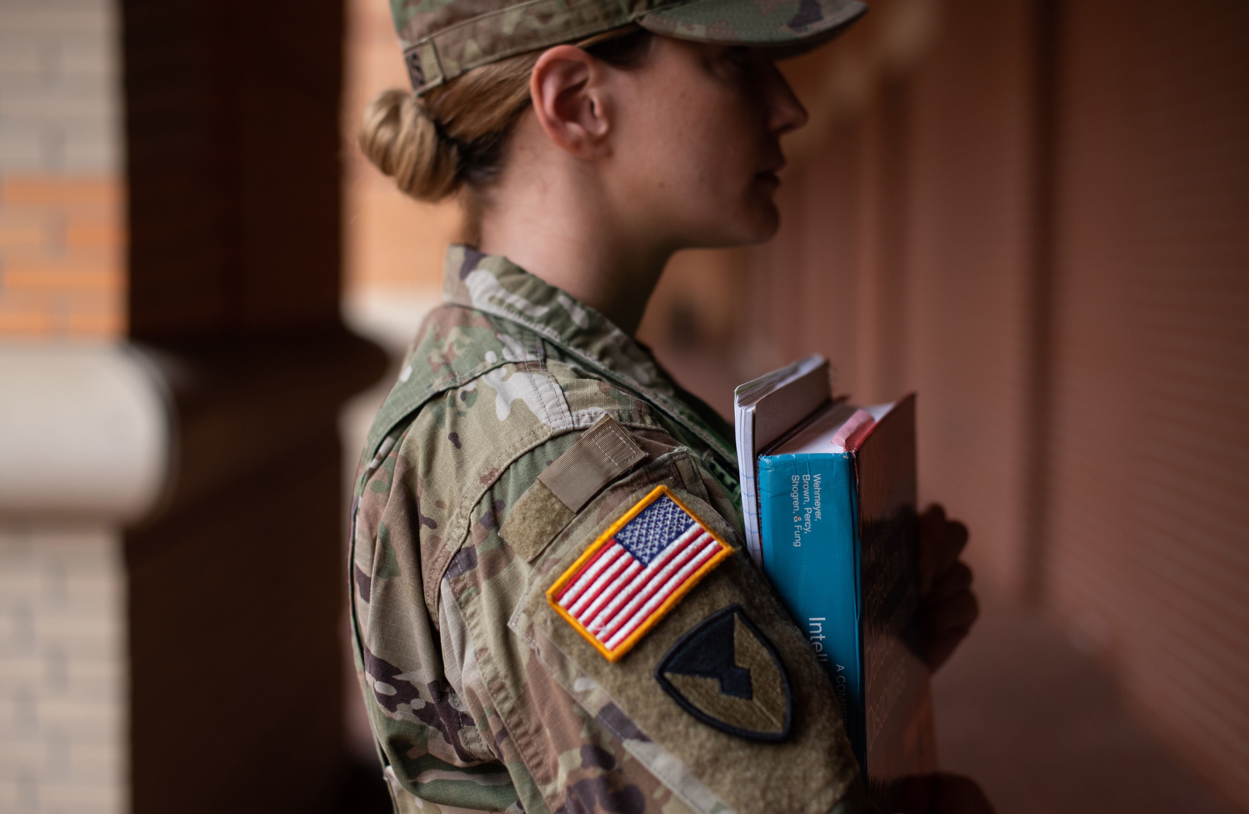 Student veteran poses in uniform and holding books